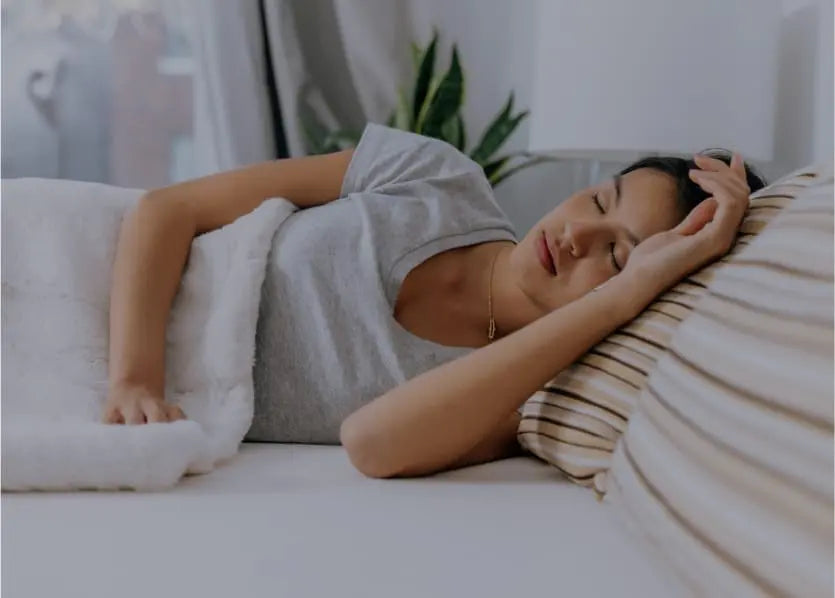 Woman in grey pyjamas sleeping with her head on an Essentia pillow