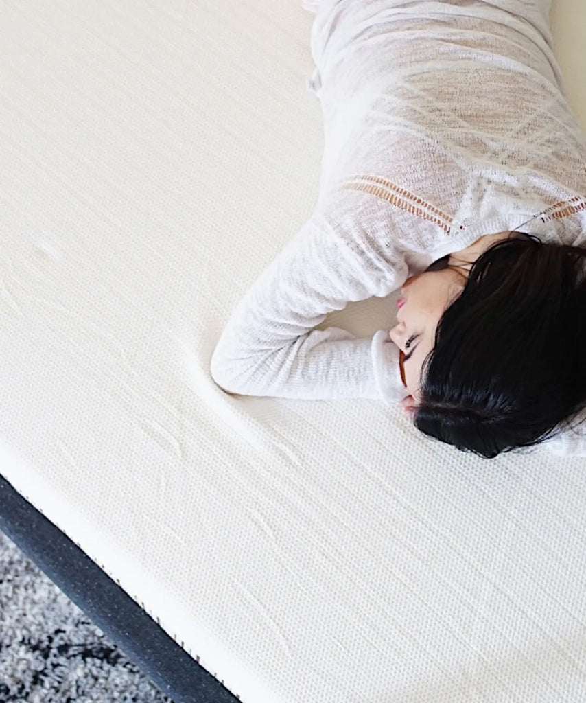 Woman in a white shirt napping face down on a Essentia mattress