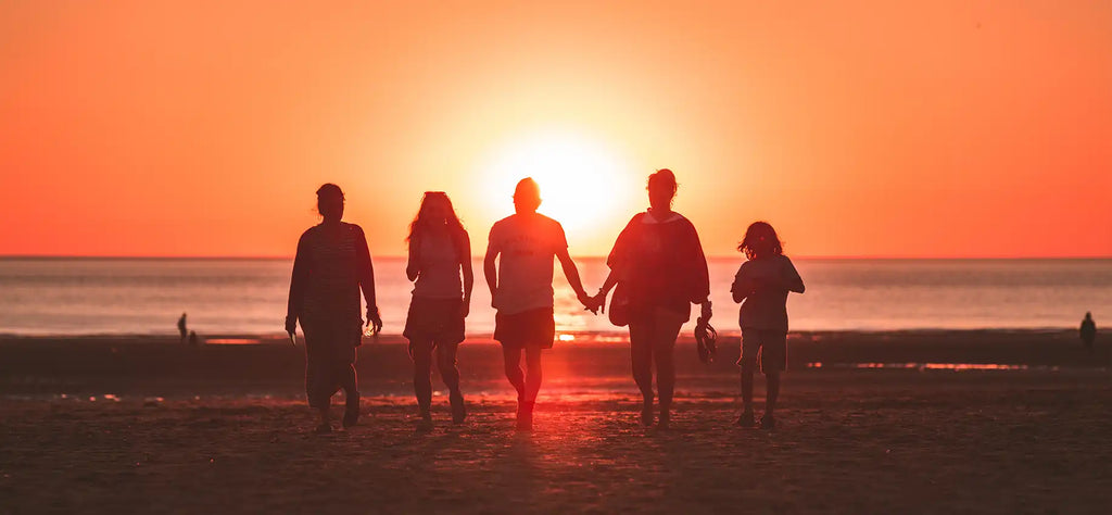 Friends walking on beach at sunset.