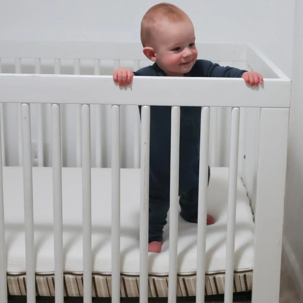 Baby standing in crib on a LaLa organic crib mattress