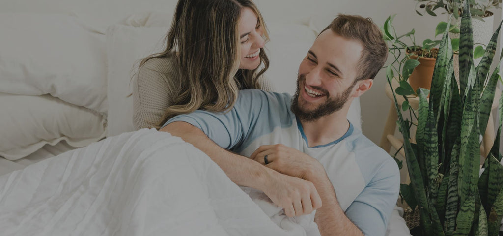 Man and woman waking up, laughing and smiling together while cuddling.