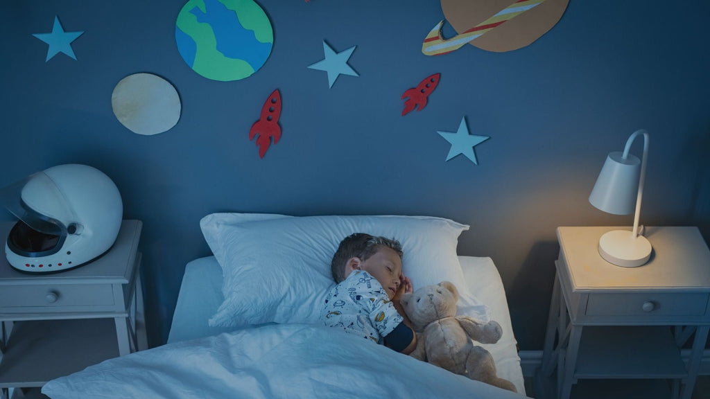 Child sleeping peacefully in his serene bedroom with the planets and stars on the wall.