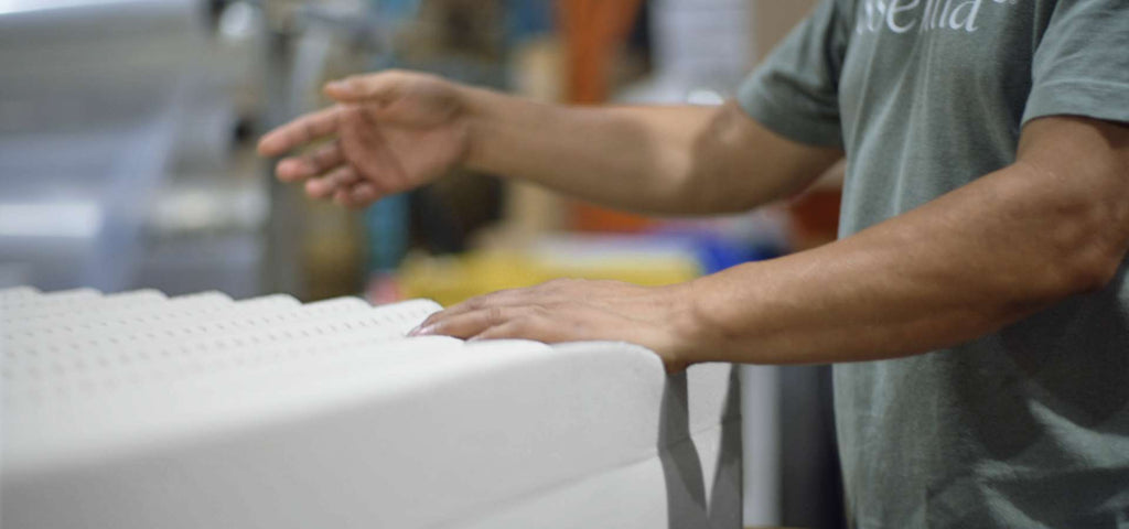 Man shown layering foam together to make a mattress without springs