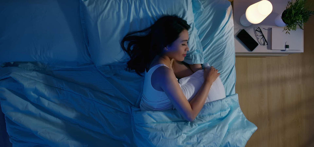 Woman sleeping in bed with blue sheets