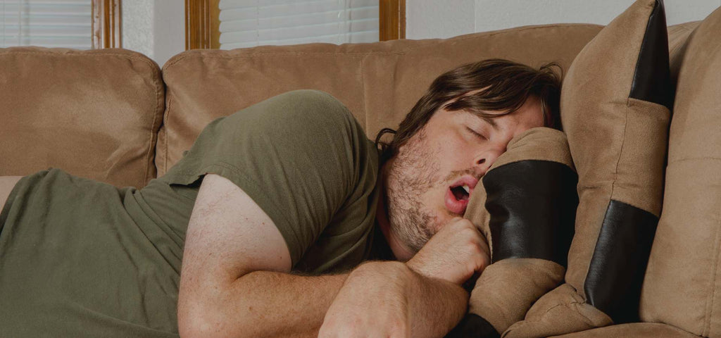 Man shown napping on the couch with his mouth open