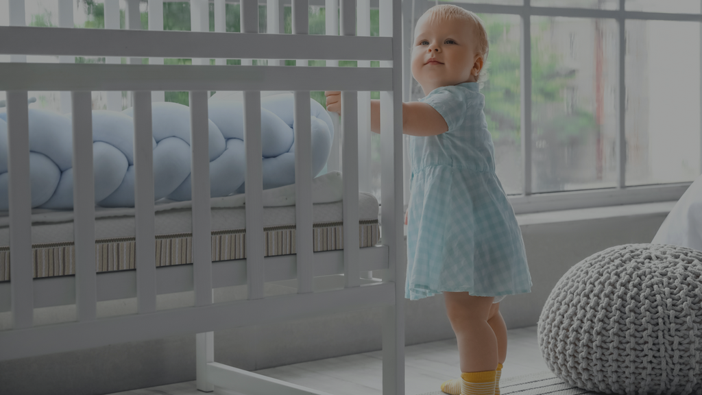 Toddler standing next to a crib