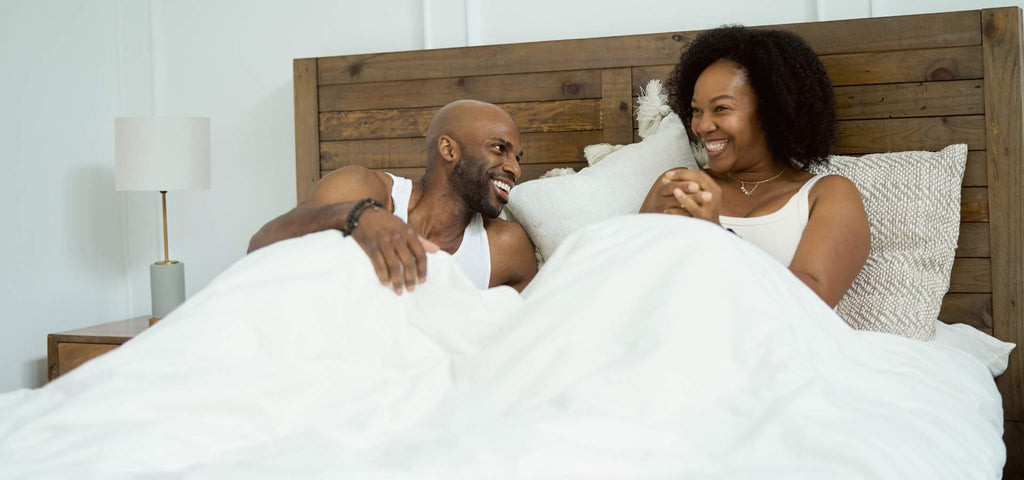 Man and woman waking up and smiling at each other in bed