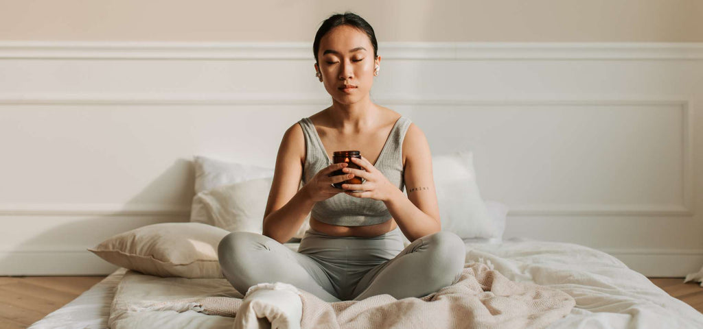 Woman meditating while holding a candle and sitting in bed
