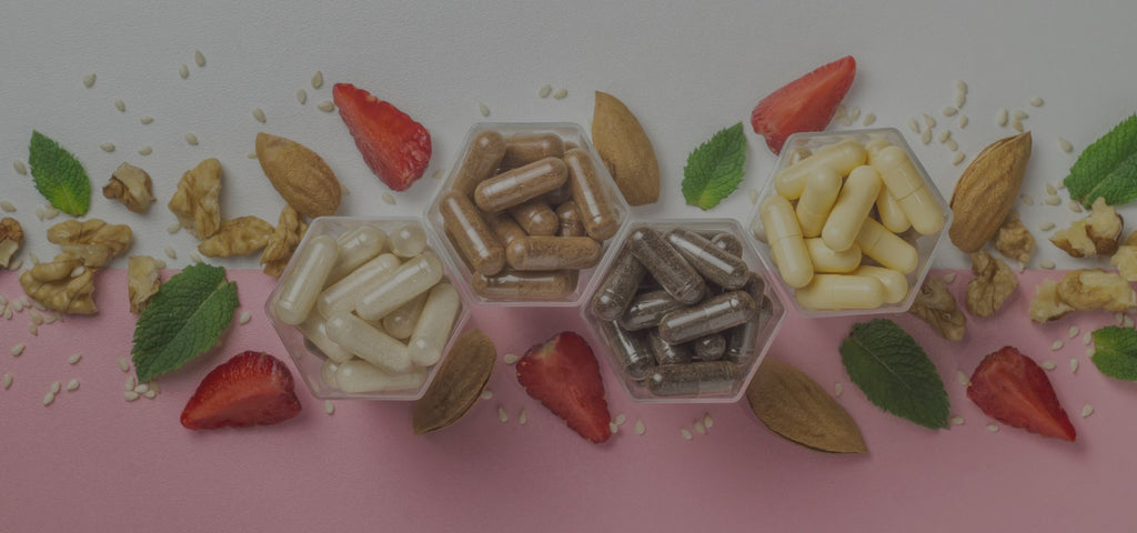 Organic supplements and almonds, sesame seeds, mint, and dried strawberries artfully arranged on a half pink, half white background