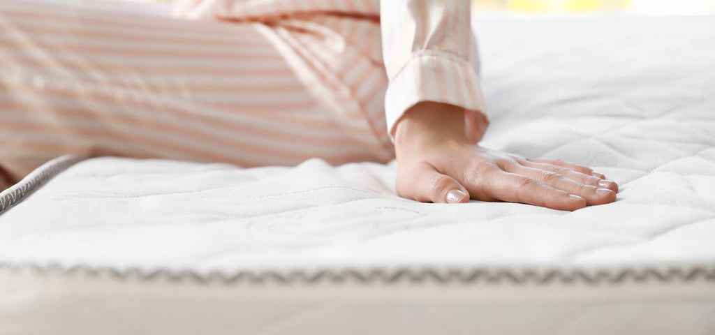 Close Up of a Woman sitting on the edge of her bed.