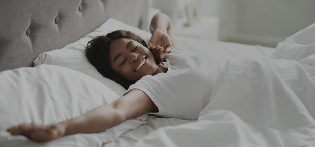Woman smiling in bed and stretching