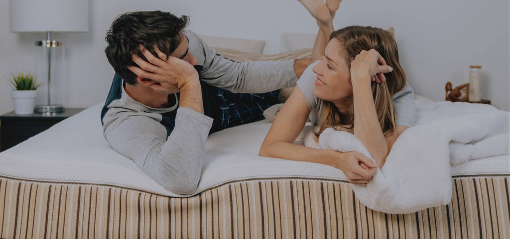 A couple trying out a comfortable new mattress while talking about how much the mattress costs.