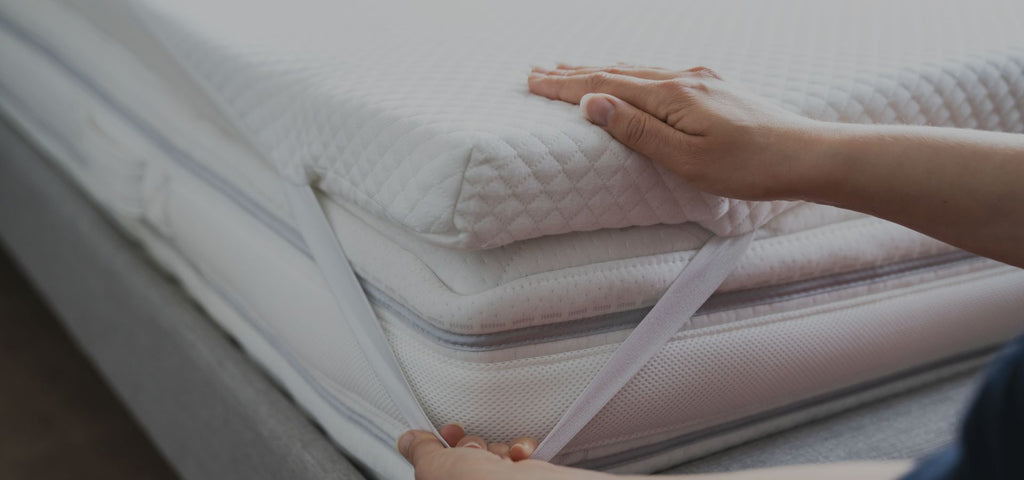 Woman putting a topper on her mattress and attaching it with the elastic strap