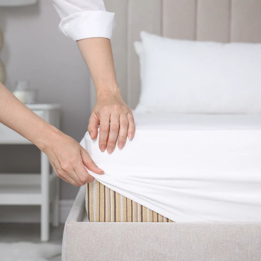 Close up image of a woman putting GOTS certified organic sheets on her Essentia organic mattress