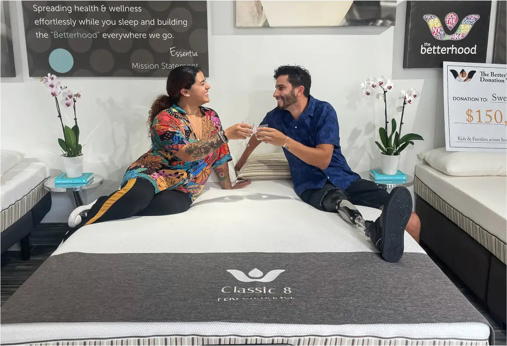 A couple drinking champagne sitting on a Essentia mattress