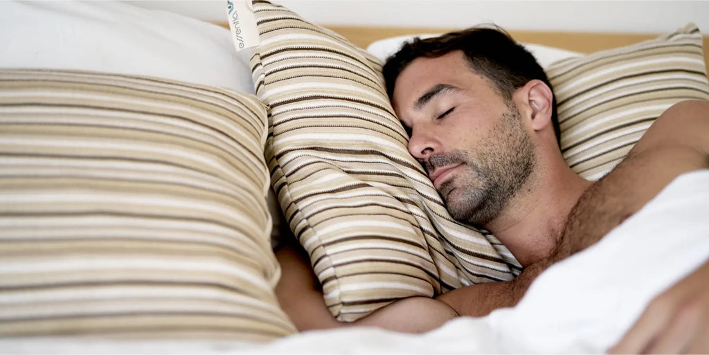 A man fast asleep with is head deep in an Essentia pillow