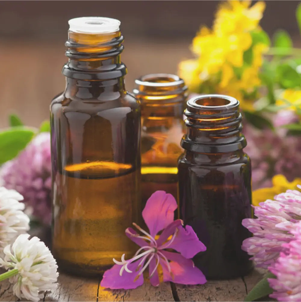 Bottles of Essentia oils sit on a table surrounded by flowers