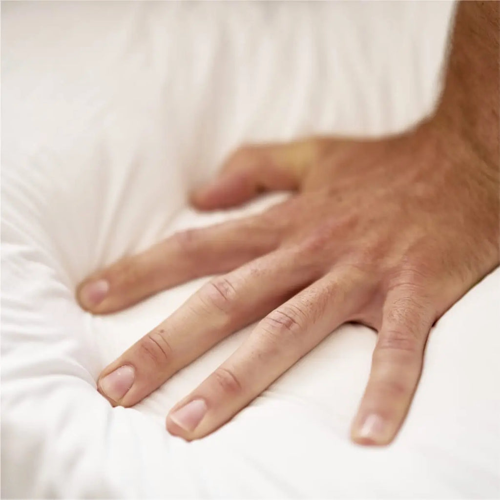 Hand pushing down on a mattress to test the softness