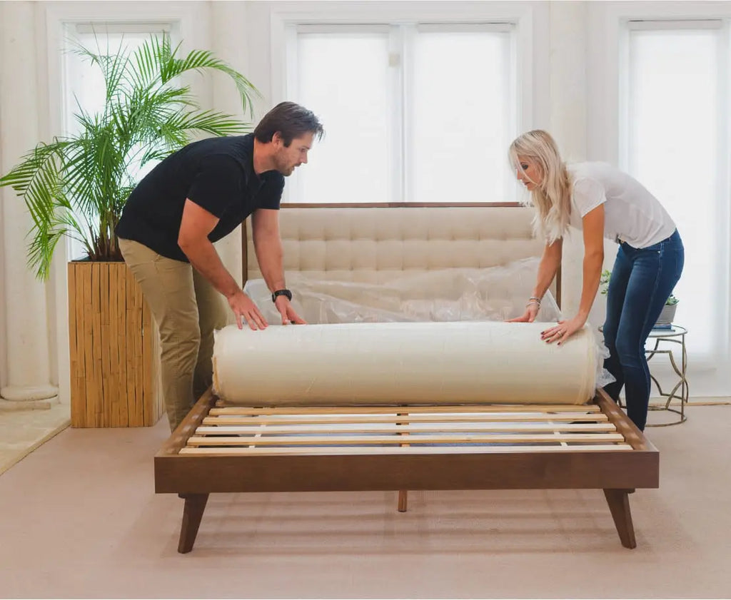 Couple unroll their new Essentia organic mattress onto their bed